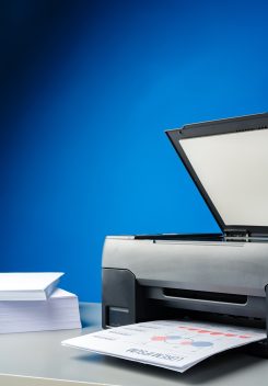 Laser printer on desk against blue background close up